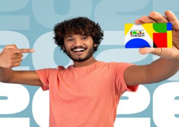 Homem sorri segurando o cartão do Bolsa Família diante do número 2026, em referência ao calendário de pagamentos de junho.