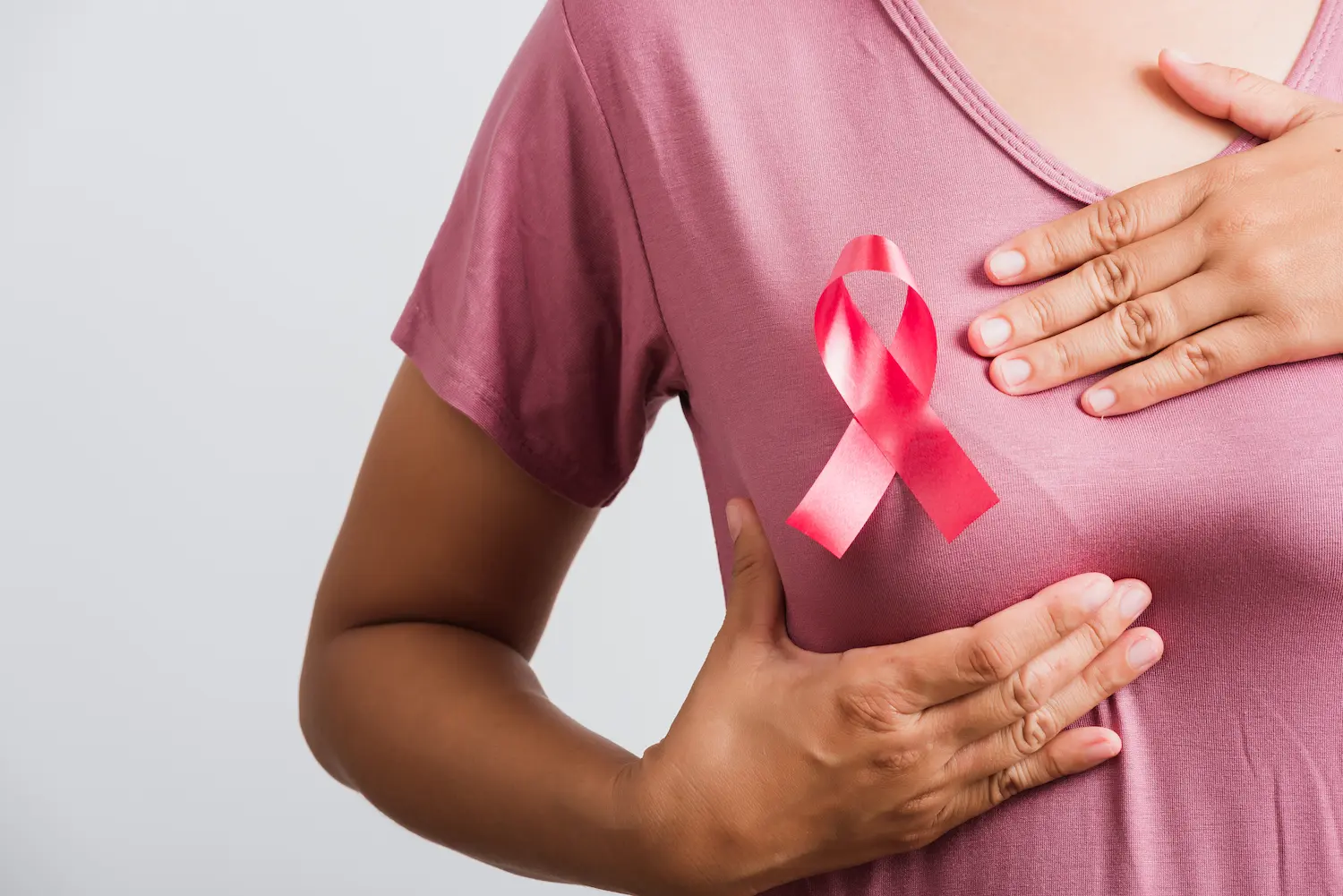 Pessoa com laço rosa na roupa durante campanha de conscientização sobre o câncer de mama.