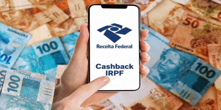 Mão segura celular com a marca da Receita Federal e o texto Cashback IRPF, sobre fundo de cédulas de real
