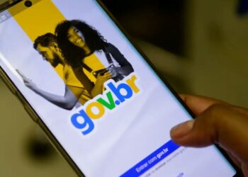 Tela de login do aplicativo gov.br aberta no celular segurado pela mão do usuário