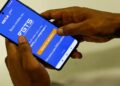 Pessoa segura o celular com o aplicativo do FGTS da Caixa aberto, em referência ao uso do fundo como garantia no Consignado CLT