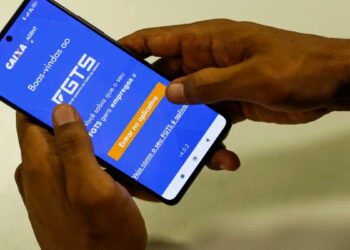 Pessoa segura o celular com o aplicativo do FGTS da Caixa aberto, em referência ao uso do fundo como garantia no Consignado CLT