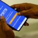 Pessoa segura o celular com o aplicativo do FGTS da Caixa aberto, em referência ao uso do fundo como garantia no Consignado CLT