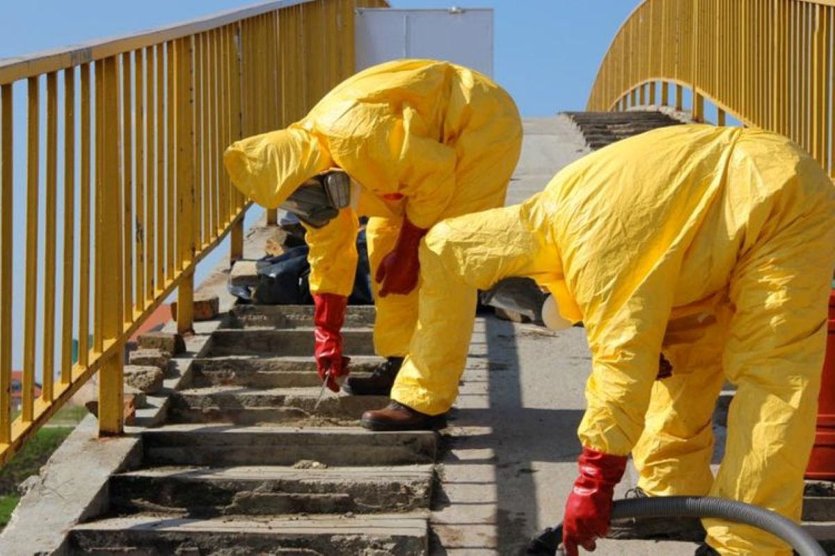 Trabalhadores com roupas de proteção amarelas atuam em atividade insalubre