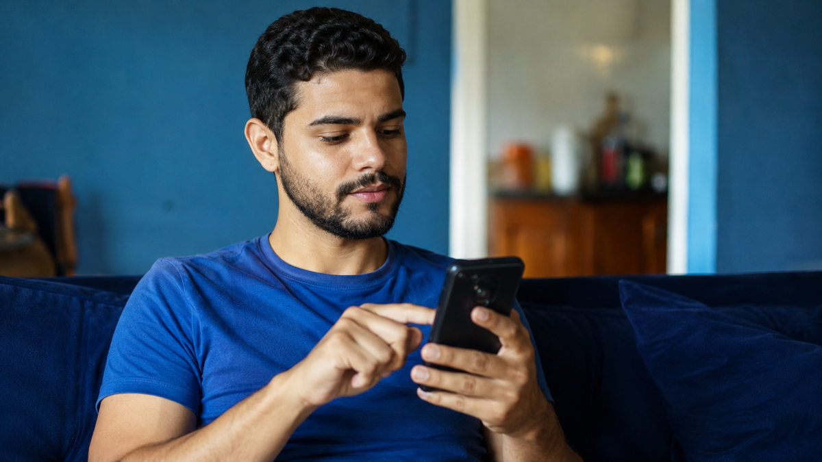 Homem mexendo no celular sentado no sofá