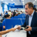Idoso é atendido no balcão de um órgão público ao apresentar um documento, tema do projeto de gratuidade para a terceira idade.