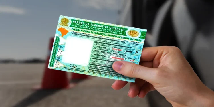 Mão segura a Carteira Nacional de Habilitação ao lado de um carro, documento que agora pode ser renovado gratuitamente por bons condutores