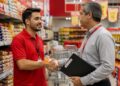 Funcionário de supermercado cumprimenta gestor com aperto de mão entre prateleiras