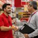 Funcionário de supermercado cumprimenta gestor com aperto de mão entre prateleiras