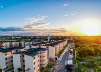 Vista aérea de conjunto habitacional do Minha Casa, Minha Vida ao pôr do sol, representando a proposta de aluguel social no programa.