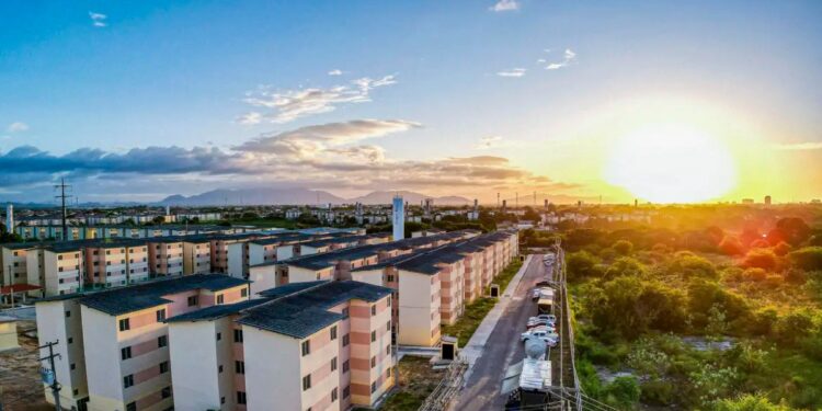 Vista aérea de conjunto habitacional do Minha Casa, Minha Vida ao pôr do sol, representando a proposta de aluguel social no programa.