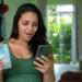 Mulher surpresa confere o celular segurando notas de cem reais
