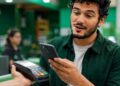 Homem paga aproximando o celular da maquininha; modalidade perde o limite de R$ 500 com a nova regra do Banco Central