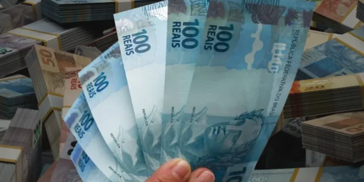 Mão segura notas de R$ 100, ilustrando as novas regras previstas para o Imposto de Renda