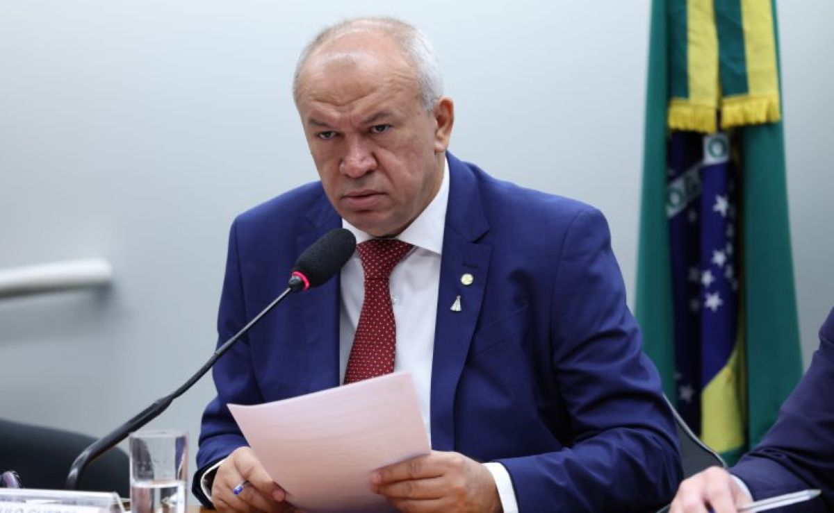 Parlamentar fala ao microfone segurando documentos durante sessão na Câmara