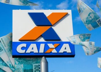 Imagem ilustrativa com a placa do logotipo da Caixa Econômica Federal cercada por cédulas de cem reais, em referência ao pagamento do Bolsa Família.