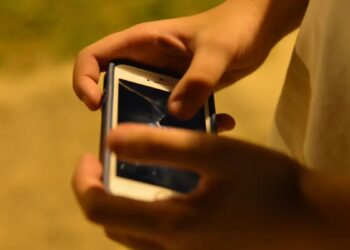 Pessoa mexe no celular ao ar livre, representando o uso de apostas esportivas alvo da notificação do governo na Copa