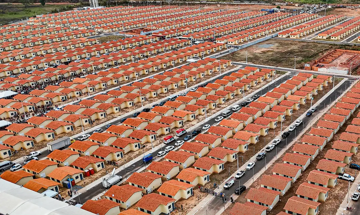 Vista aérea de centenas de casas do Minha Casa, Minha Vida, representando o alcance do programa habitacional e o projeto de aluguel social.