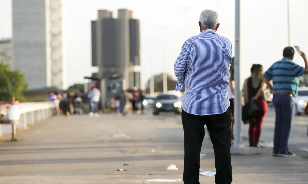 Homem idoso caminha em via pública de uma cidade, representando os beneficiários do projeto de gratuidade de documentos.
