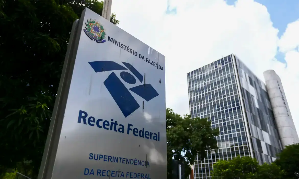 Placa da Receita Federal em frente a prédio público, ilustrando que empresas já existentes não precisarão alterar seus CNPJs.