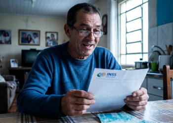 Aposentado confere documento do INSS em casa, verificando descontos para pedir o ressarcimento.