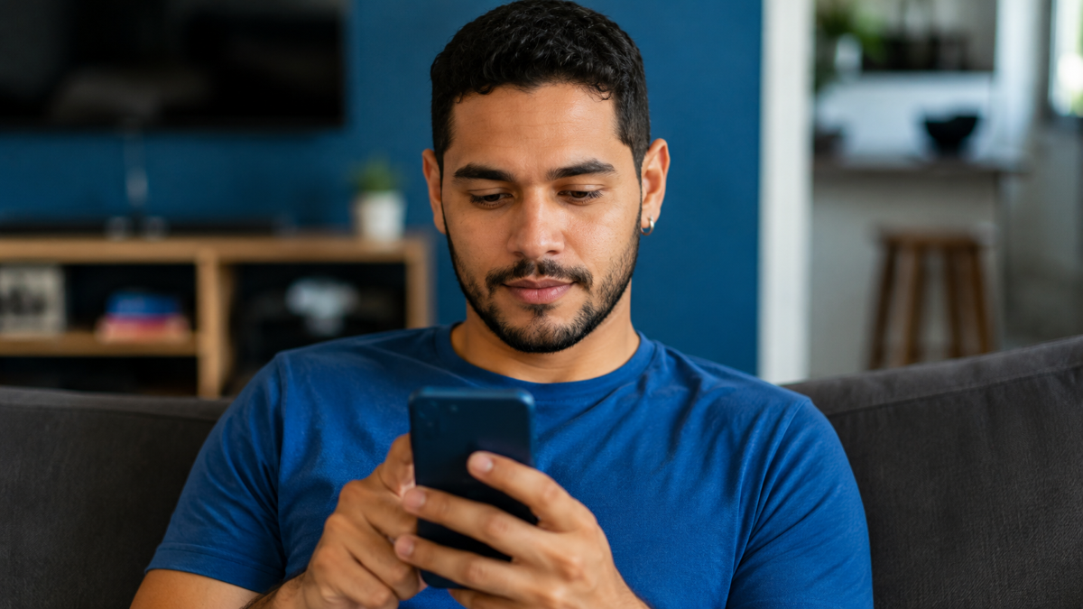 Homem acessa o celular no sofá para usar a versão digital do documento
