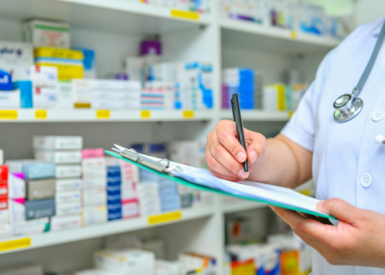 Profissional da saúde realizando inventário de medicamentos em farmácia clínica.