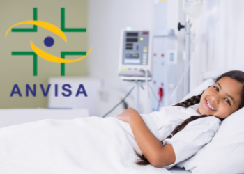 Criança internada sorrindo em hospital com logo da Anvisa em destaque.