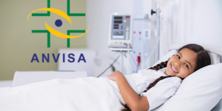 Criança internada sorrindo em hospital com logo da Anvisa em destaque.
