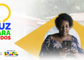 Mulher sorrindo com celular nas mãos, fundo de casa simples, logo Luz para Todos e Governo do Brasil ao lado.