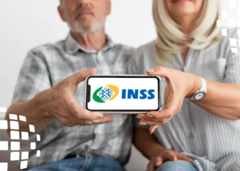 Dois idosos seguram celular mostrando logotipo do INSS centralizado na tela