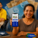 Mulher mostrando celular com app Bolsa Família, homem cadeirante ao fundo, carteira de trabalho e cartão PIS/PASEP sobre a mesa