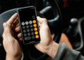 Homem usa calculadora no celular enquanto dirige carro.