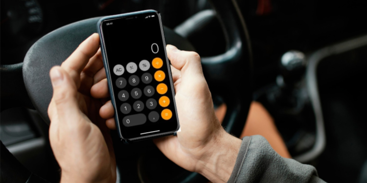 Homem usa calculadora no celular enquanto dirige carro.