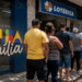 Pessoas aguardam em fila diante de uma lotérica para consultar ou receber o Bolsa Família