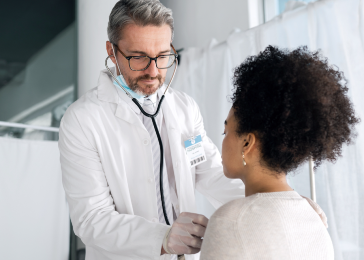 Médico realiza exame clínico com estetoscópio em consultório hospitalar.