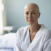 Mulher em tratamento oncológico com olhar resiliente em quarto hospitalar.