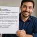 Homem jovem segura certidão negativa de débitos com brasão do Brasil e texto legível, sorrindo em escritório
