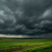 Tempestade iminente se forma sobre campo verde em zona rural.