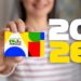 Mulher segura cartão do Bolsa Família colorido, com ano 2026 em destaque ao lado