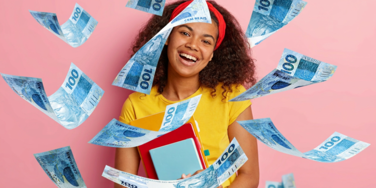 Jovem sorridente com livros cercada por notas de 100 reais em fundo rosa.