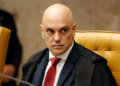 Alexandre de Moraes sentado em cadeira amarela no STF, usando terno e gravata vermelha, expressão séria.