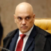 Alexandre de Moraes sentado em cadeira amarela no STF, usando terno e gravata vermelha, expressão séria.