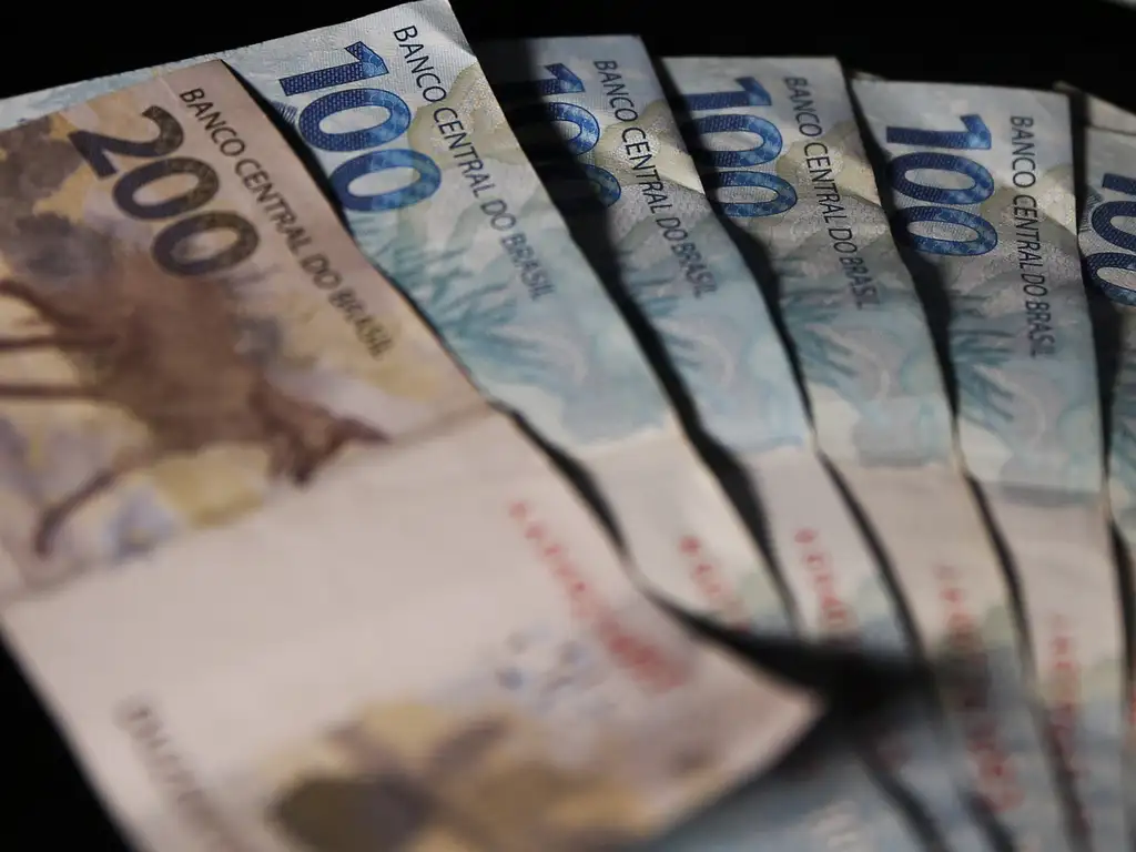 Várias cédulas de 100 e 200 reais do Banco Central do Brasil dispostas em leque