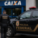 agente da Polícia Federal conduz homem algemado próximo a viatura preta diante de agência da Caixa