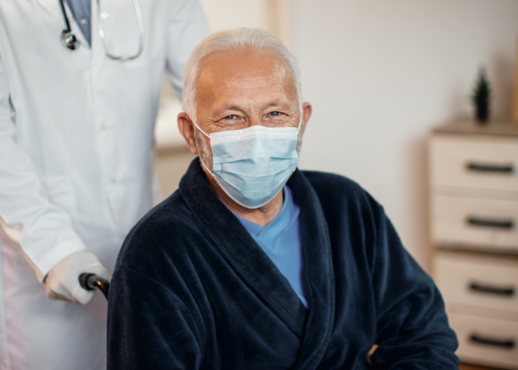 Idoso com máscara sendo atendido por médico em clínica.