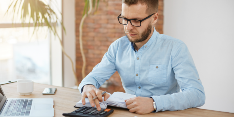 Jovem analisa finanças em escritório moderno com calculadora.