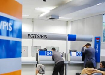 Pessoas em fila e funcionários atendendo guichês numerados 04 e 05 em agência FGTS/PIS