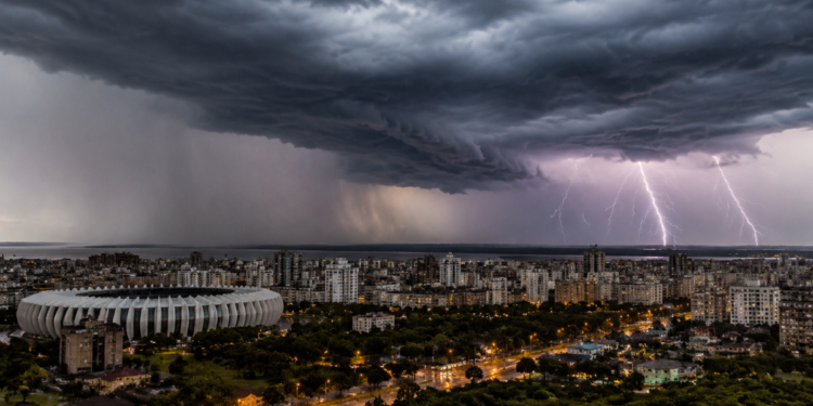 Céu escuro com nuvens densas e relâmpagos atingindo cidade de Porto Alegre e estádio em destaque