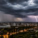 Céu escuro com nuvens densas e relâmpagos atingindo cidade de Porto Alegre e estádio em destaque
